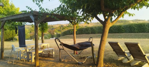 Espace extérieur avec table en bois, hamac et chaises longues sous les arbres au Domaine d' Essendieras.