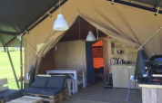 Interior of a safari tent with wooden furniture, sofas, and dining area at Domaine d’ Essendieras, France.