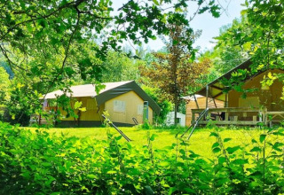 Safaritent met badkamer op camping La Prade in Frankrijk, omgeven door groene natuur en bomen.