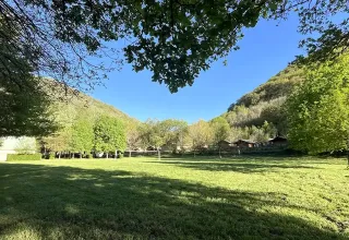 Vista su prato, alberi e colline presso Safaritent met badkamer, Campeggio La Prade, Francia, con cielo sereno.