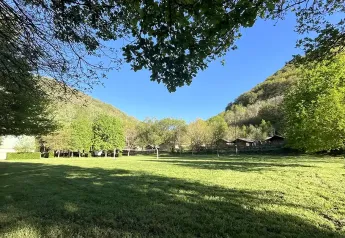 Vista su prato, alberi e colline presso Safaritent met badkamer, Campeggio La Prade, Francia, con cielo sereno.