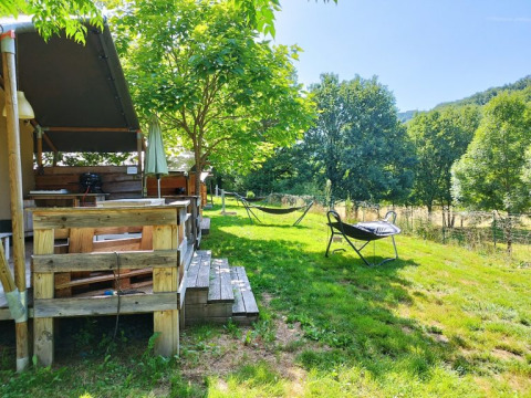 Buitenaanzicht van een safaritent met badkamer op Camping La Prade in Frankrijk, omringd door groen.