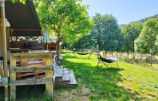 Vista all'aperto di una tenda safari con bagno al campeggio La Prade in Francia, circondata dal verde.