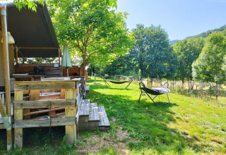 Vista all'aperto di una tenda safari con bagno al campeggio La Prade in Francia, circondata dal verde.