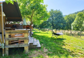 Buitenaanzicht van een safaritent met badkamer op camping La Prade in Frankrijk, omgeven door natuur.