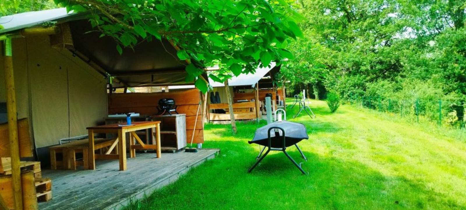 Safaritent met badkamer op Camping La Prade in Frankrijk, met terras, barbecue en groene omgeving.