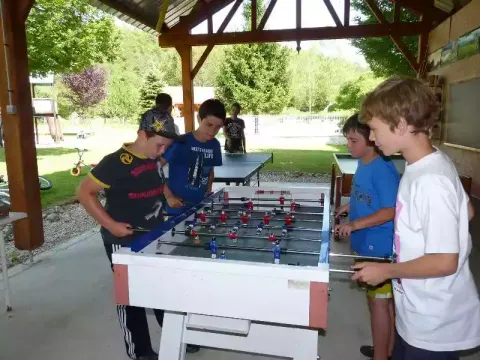 Bambini che giocano al calcio balilla al coperto nel campeggio La Faz, Bourgogne-Franche-Comté, Francia.