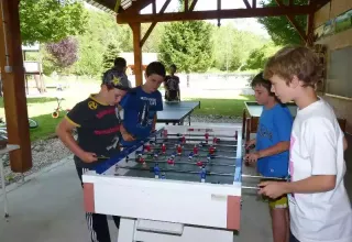 Bambini che giocano al calcio balilla al coperto nel campeggio La Faz, Bourgogne-Franche-Comté, Francia.