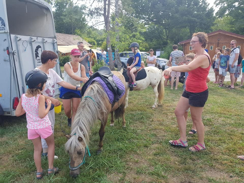 Bambini e adulti si divertono a cavalcare pony al campeggio La Faz in Borgogna-Franca Contea, Francia.