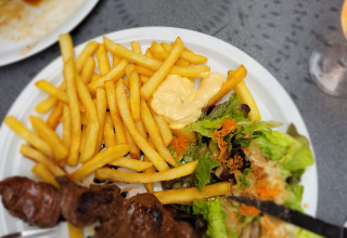 Un piatto con patatine fritte, insalata e spiedino di carne servito su un tavolo al campeggio La Faz, Francia.