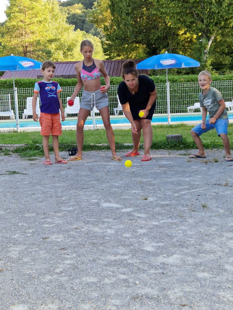 Bambini e una donna giocano a bocce vicino alla piscina al campeggio La Faz in Borgogna, Francia.