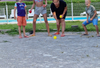 Bambini e una donna giocano a bocce vicino alla piscina al campeggio La Faz in Borgogna, Francia.
