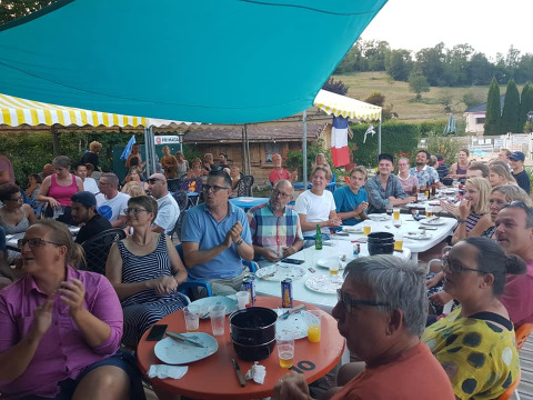 Ospiti riuniti sotto un tendone condividono un pasto conviviale al campeggio La Faz in Borgogna-Franca Contea, Francia.