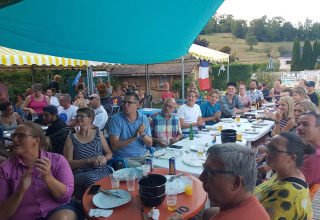Ospiti riuniti sotto un tendone condividono un pasto conviviale al campeggio La Faz in Borgogna-Franca Contea, Francia.