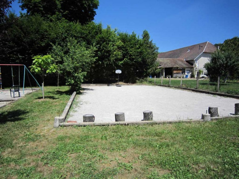 Parco giochi con altalene, campo sabbioso e sfondo rurale al Campeggio La Faz a Bourgogne-Franche-Comté, Francia.