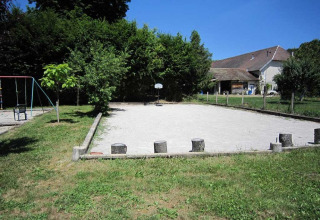 Parco giochi con altalene, campo sabbioso e sfondo rurale al Campeggio La Faz a Bourgogne-Franche-Comté, Francia.