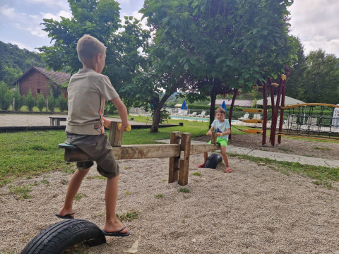 Due bambini giocano su un'altalena nel parco giochi del campeggio 'La Faz' tra gli alberi in Francia.