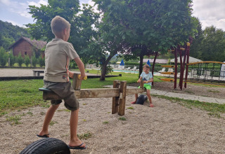 Due bambini giocano su un'altalena nel parco giochi del campeggio 'La Faz' tra gli alberi in Francia.