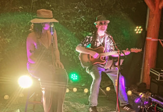 Due musicisti si esibiscono su un palco all'aperto al Campsite La Faz in Bourgogne-Franche-Comté, Francia, di notte.