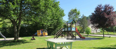 Area giochi del campeggio La Faz in Borgogna-Franca Contea, Francia, con scivolo e alberi ombreggianti.