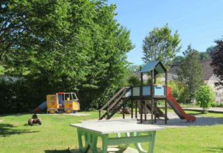 Area giochi del campeggio La Faz in Borgogna-Franca Contea, Francia, con scivolo e alberi ombreggianti.