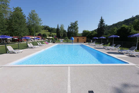 Piscina all'aperto con lettini e ombrelloni al campeggio La Faz in Borgogna-Franca Contea, Francia.