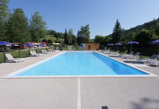 Piscina al aire libre con tumbonas y sombrillas en el camping La Faz en Bourgogne-Franche-Comté, Francia.