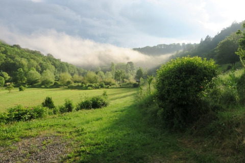 Vista su una valle verde e colline con nebbia mattutina al campeggio La Faz in Bourgogne-Franche-Comté, Francia.