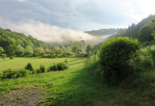Vista su una valle verde e colline con nebbia mattutina al campeggio La Faz in Bourgogne-Franche-Comté, Francia.