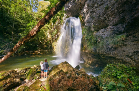 Due persone osservano una cascata immersa nella natura lussureggiante vicino a Orgelet, Francia.