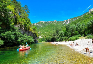 Campeggio La Faz in Bourgogne-Franche-Comté, Francia, con famiglie che nuotano e fanno canoa sul fiume.