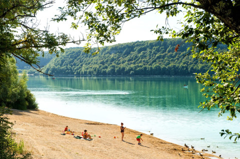 Famiglie si rilassano e giocano sulla spiaggia sabbiosa vicino a un lago tranquillo in Borgogna-Franca Contea, Francia.