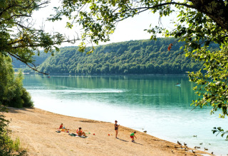 Famiglie si rilassano e giocano sulla spiaggia sabbiosa vicino a un lago tranquillo in Borgogna-Franca Contea, Francia.