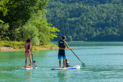 Famiglia sul paddleboard in un lago vicino al campeggio La Faz in Bourgogne-Franche-Comté, Francia.