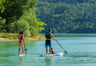 Famiglia sul paddleboard in un lago vicino al campeggio La Faz in Bourgogne-Franche-Comté, Francia.