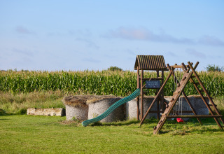 Legeplads med rutsjebane og gynger foran en stor majsmark på BoerenBed College Farm, feriepark i England.