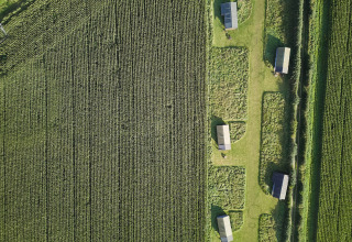 Luftaufnahme des Ferienparks BoerenBed College Farm in Ostengland mit Hütten zwischen grünen Feldern.