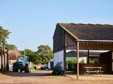 Un tracteur bleu et des bâtiments agricoles à BoerenBed College Farm, parc de vacances dans l'est de l'Angleterre.
