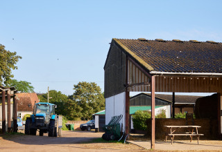 A blue tractor and farm buildings at BoerenBed College Farm holiday park in the East of England, UK.
