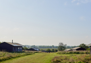 Vista sui prati e sulle cabine del parco vacanze BoerenBed College Farm nell'Est dell'Inghilterra sotto cielo limpido.