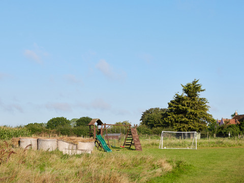 Aire de jeux extérieure avec toboggan, bottes de foin et cage de foot au BoerenBed College Farm en Angleterre.