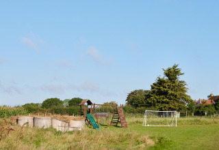 Aire de jeux extérieure avec toboggan, bottes de foin et cage de foot au BoerenBed College Farm en Angleterre.