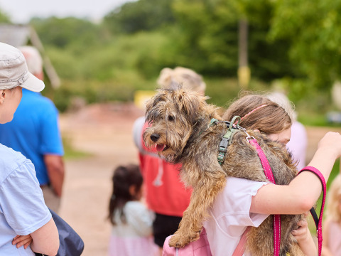 Una niña lleva un perro sobre el hombro en el parque vacacional BoerenBed Billingsmoor Farm en el suroeste de Inglaterra.