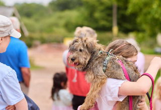 Ein Mädchen trägt einen Hund auf der Schulter im Ferienpark BoerenBed Billingsmoor Farm in Südwestengland.
