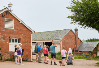 Gezinnen met kinderen verzamelen zich bij rode bakstenen boerderijgebouwen op BoerenBed Billingsmoor Farm, VK.