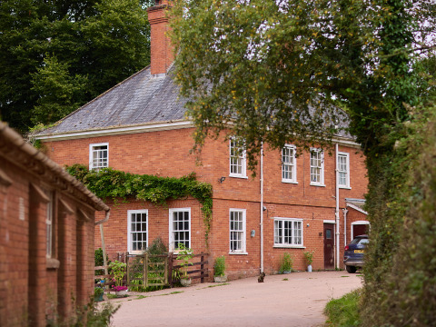 Casa rural de ladrillo rojo con jardín en BoerenBed Billingsmoor Farm, en el suroeste de Inglaterra, Reino Unido.