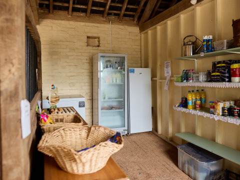 Binnenfoto van een kleine boerderijwinkel bij BoerenBed Billingsmoor Farm met schappen en koelkast.