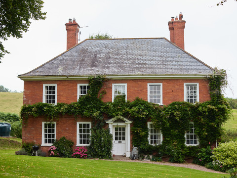 Charmant huis van rode bakstenen met klimplanten, gefotografeerd op Billingsmoor Farm in Zuidwest-Engeland.