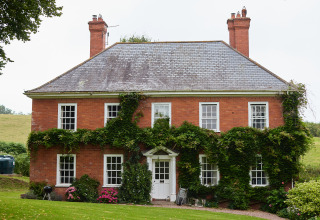 Charmante maison en briques rouges recouverte de plantes grimpantes à Billingsmoor Farm, sud-ouest de l’Angleterre.