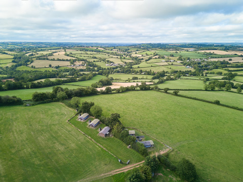 Vue aérienne des champs verdoyants et des lodges à BoerenBed Billingsmoor Farm dans le sud-ouest de l’Angleterre.